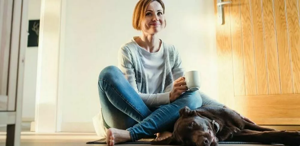 En dame sitter på bakken sammen med en hund. Foto